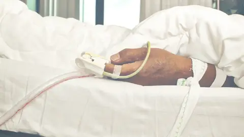 Persona mayor sujeta a una cama Persona mayor sujeta a una cama