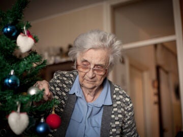 Mujer mayor decorando un árbol de Navidad
