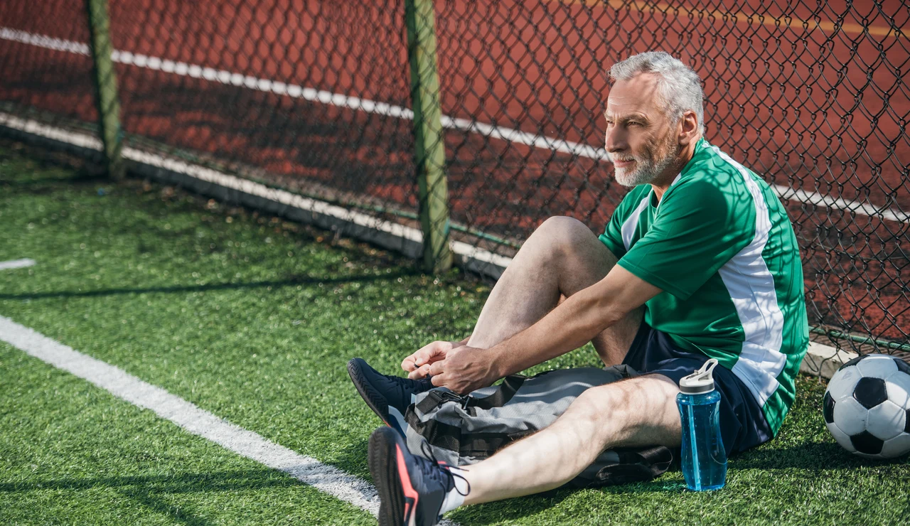 Un hombre mayor atándose unas botas de fútbol