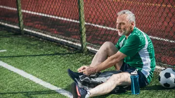 Un hombre mayor atándose unas botas de fútbol