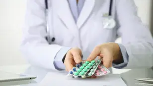 Médico con diferentes pastillas en la mano