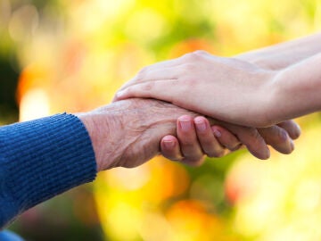 Mujer mayor dando la mano a una mujer joven