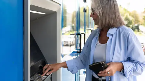 Señora sacando dinero de un cajero Señora sacando dinero de un cajero