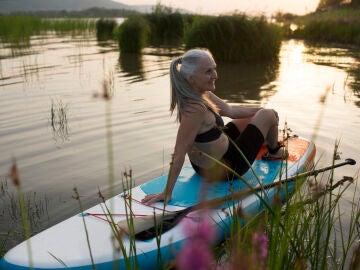 Mujer mayor sentada sobre una tabla paddle surf