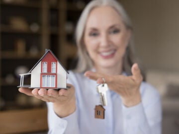 Mujer mayor posa con las llaves de su casa
