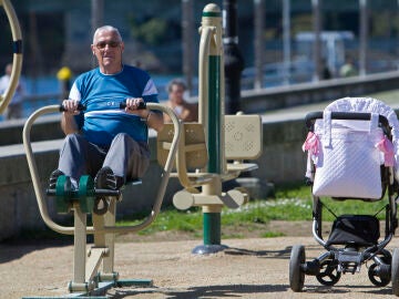 Un abuelo al lado de un carrito de bebé en un parque