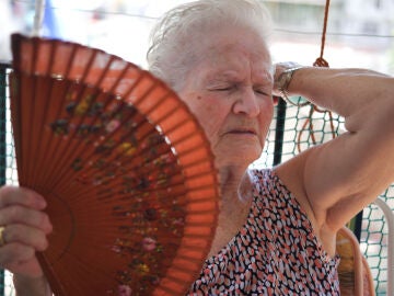 Mujer mayor con mucho calor abanic&aacute;ndose