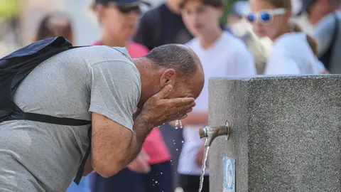 Un hombre se refresca en fuente pública Un hombre se refresca en fuente pública