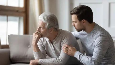 Hombre mayor preocupado junto a su hijo Hombre mayor preocupado junto a su hijo