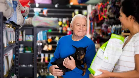 Hombre mayor comprando comida para su perro en una tienda de animales Hombre mayor comprando comida para su perro en una tienda de animales