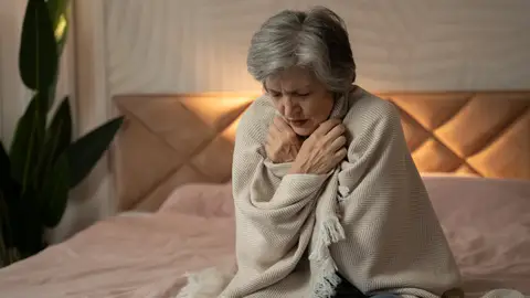 Mujer mayor tiene frío y se tapa con una manta en su casa Mujer mayor tiene frío y se tapa con una manta en su casa
