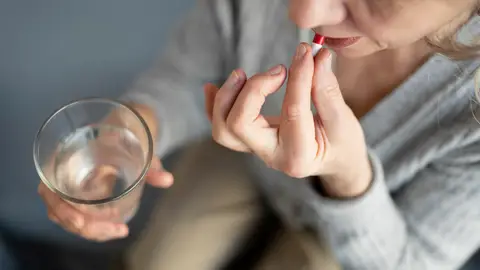 Una mujer se toma medicamentos Una mujer se toma medicamentos