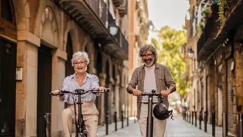 Pareja mayor disfrutando de una bicicleta y patinete Pareja mayor disfrutando de una bicicleta y patinete