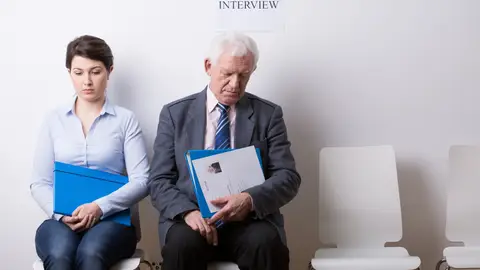 Mujer joven y hombre mayor esperando por una entrevista de trabajo Mujer joven y hombre mayor esperando por una entrevista de trabajo