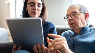 Mujer joven junto a hombre mayor viendo una Tablet