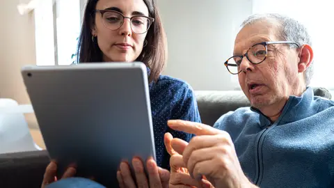 Mujer joven junto a hombre mayor viendo una Tablet Mujer joven junto a hombre mayor viendo una Tablet