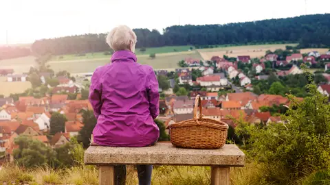 Mujer sentada en un banco contemplando una población Mujer sentada en un banco contemplando una población