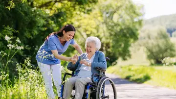 Mujer cuidadora junto a mujer mayor en silla de ruedas Mujer cuidadora junto a mujer mayor en silla de ruedas