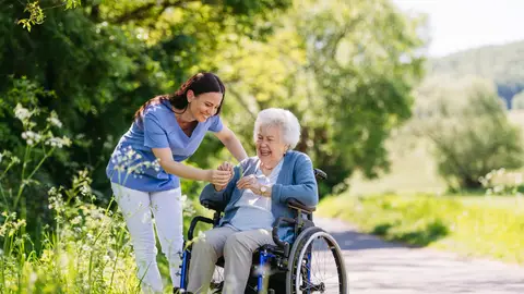 Mujer cuidadora junto a mujer mayor en silla de ruedas Mujer cuidadora junto a mujer mayor en silla de ruedas