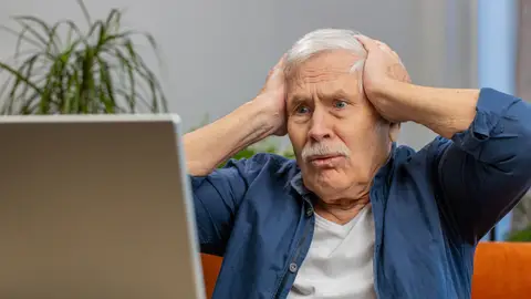 Hombre mayor preocupado delante de un ordenador portátil Hombre mayor preocupado delante de un ordenador portátil