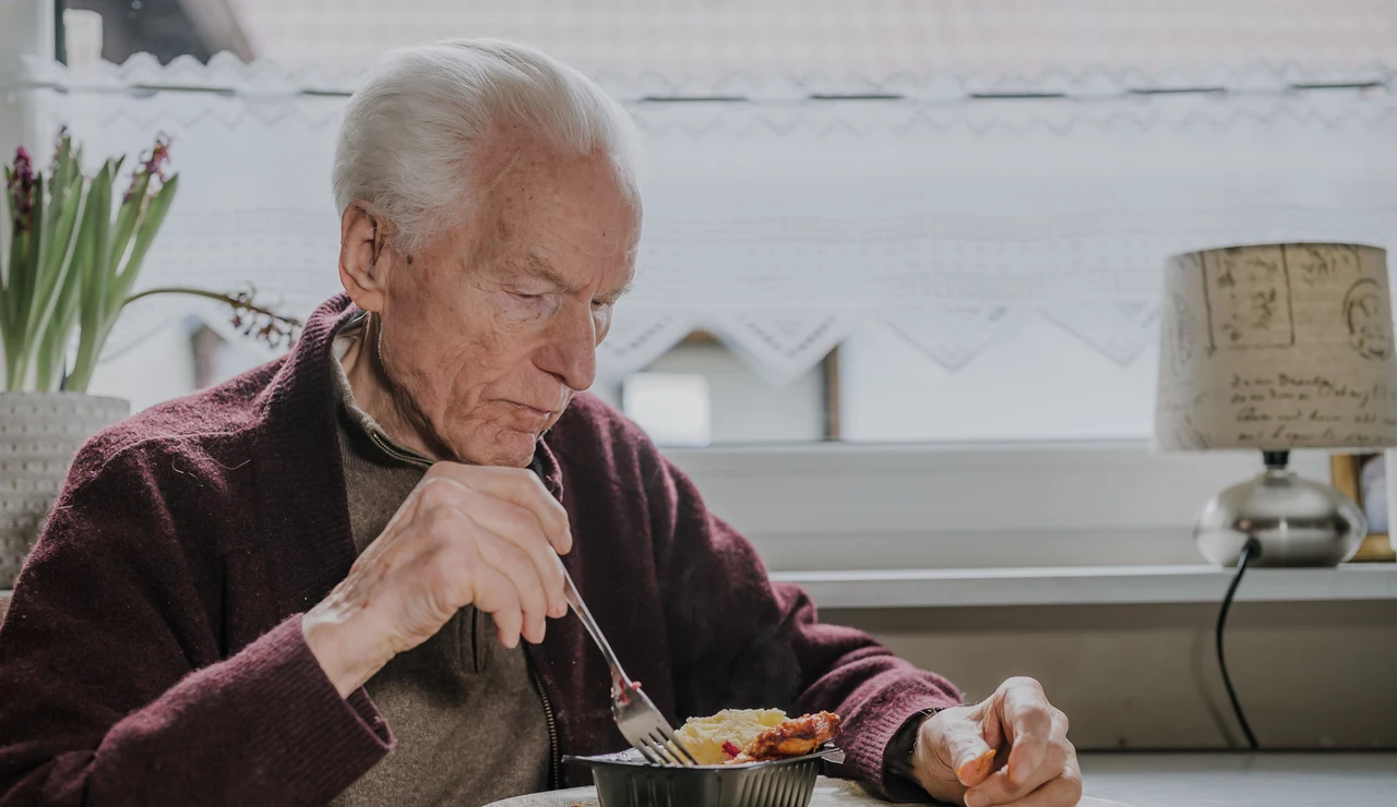 Hombre mayor comiendo solo