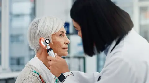 Mujer revisándose el oído Mujer revisándose el oído