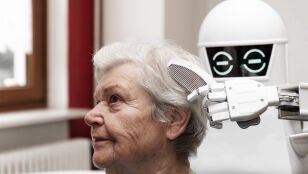 Un cuidador rob&oacute;tico est&aacute; peinando el cabello de una adulta de edad avanzada