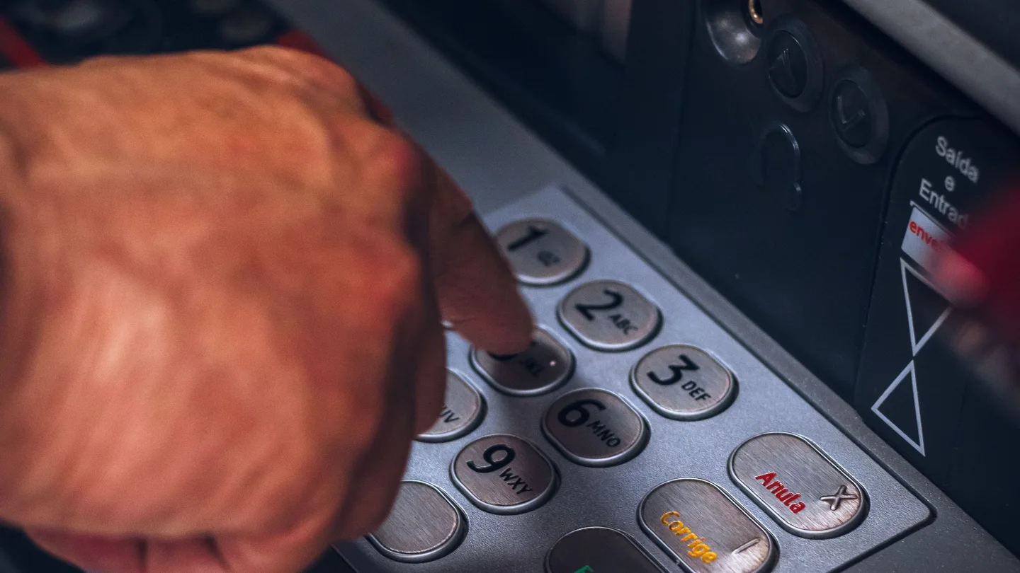 Primer plano de una mano accediendo a un cajero automático. Primer plano de una mano accediendo a un cajero automático.