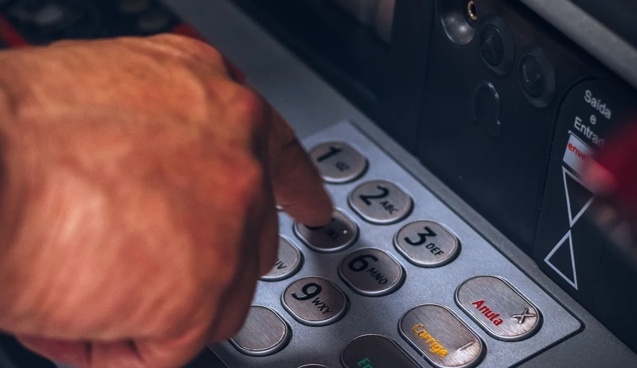 Primer plano de una mano accediendo a un cajero automático.