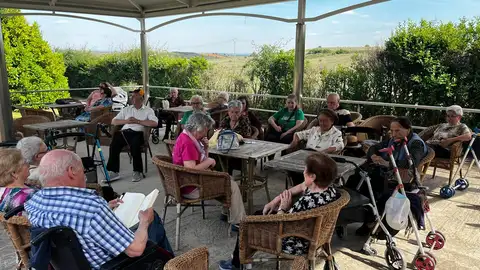 Grupo de personas en una terraza leyendo y compartiendo un rato juntos Grupo de personas en una terraza leyendo y compartiendo un rato juntos