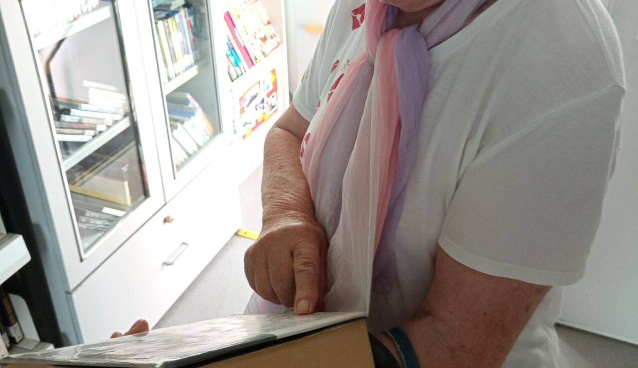 Mujer sujetando un libro mientras lee su sinopsis.