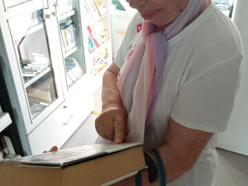 Mujer sujetando un libro mientras lee su sinopsis.