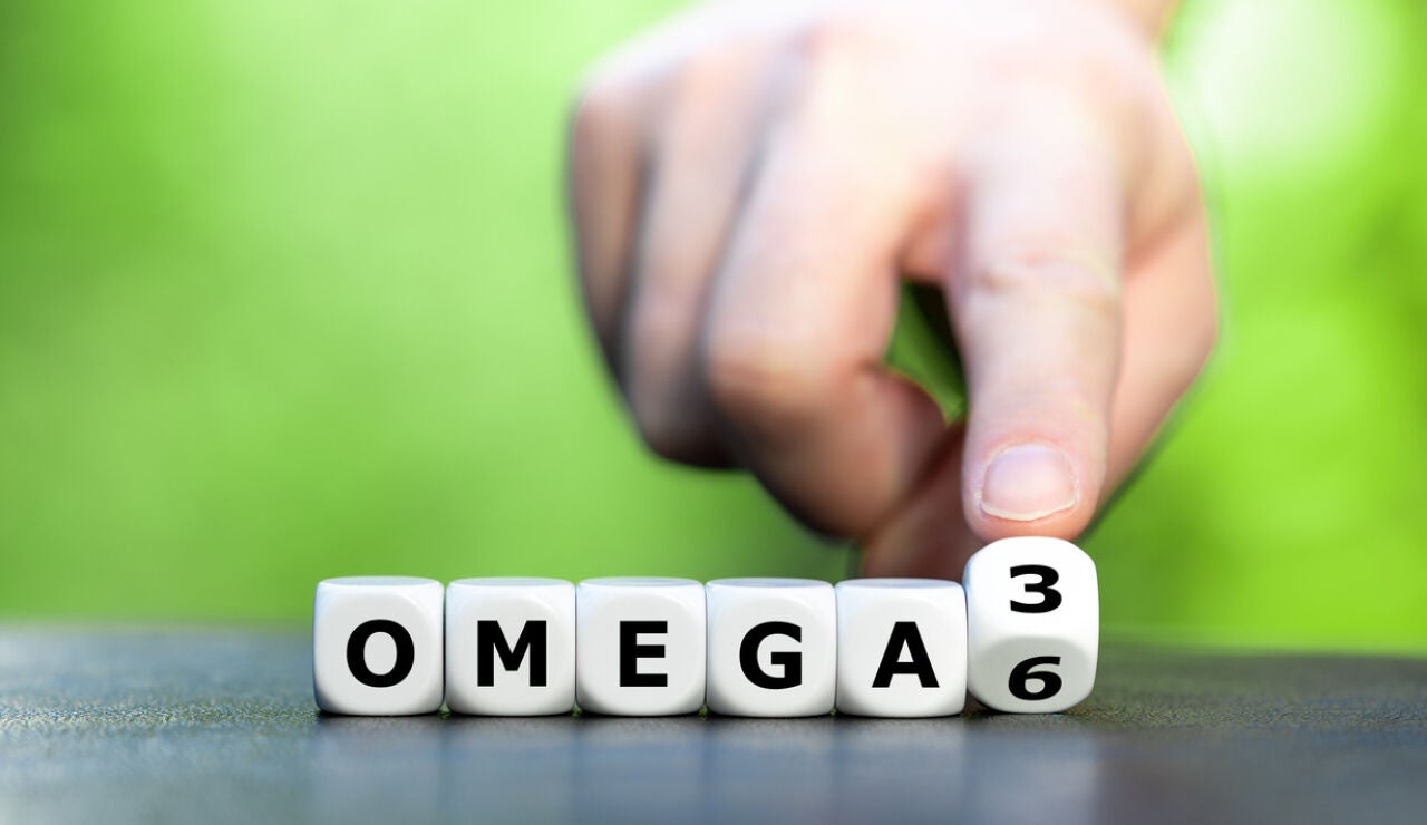 S&iacute;mbolo de la alimentaci&oacute;n saludable. La mano gira los dados y cambia la expresi&oacute;n "Omega 6" por "Omega 3". 