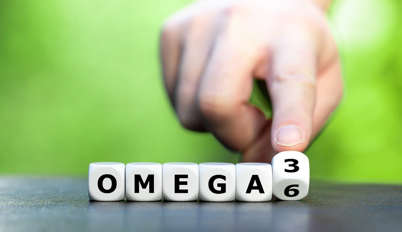 Símbolo de la alimentación saludable. La mano gira los dados y cambia la expresión "Omega 6" por "Omega 3".