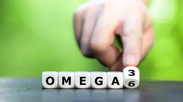 Símbolo de la alimentación saludable. La mano gira los dados y cambia la expresión "Omega 6" por "Omega 3". Símbolo de la alimentación saludable. La mano gira los dados y cambia la expresión "Omega 6" por "Omega 3".