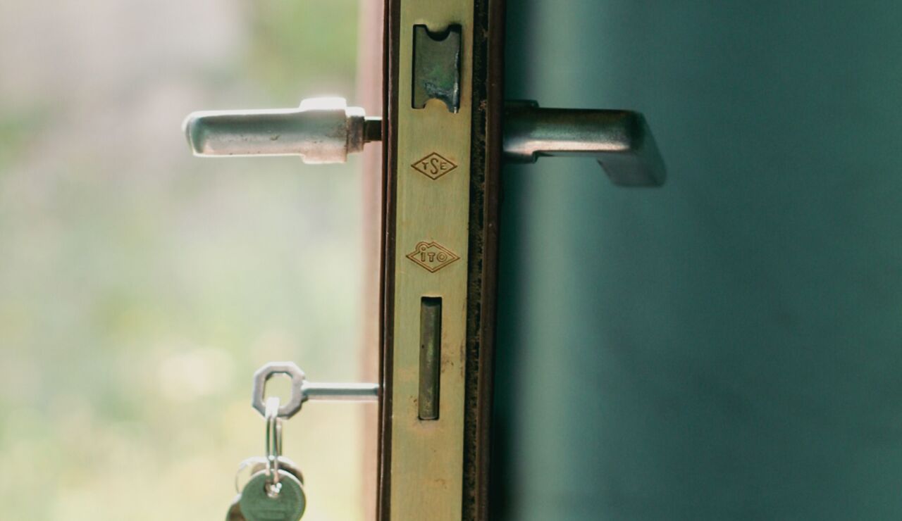 Una vista en primer plano de una cerradura de puerta con llaves insertadas, iluminada por la luz natural