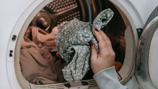 Primer plano de una mujer cargando ropa en una lavadora, destacando quehaceres dom&eacute;sticos y la rutina diaria.